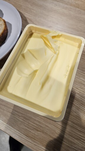Large divot in new container of butter with some scraped on the edge of the container