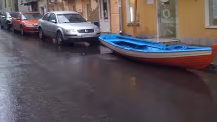 A image of a boat placed in a parking space on a street